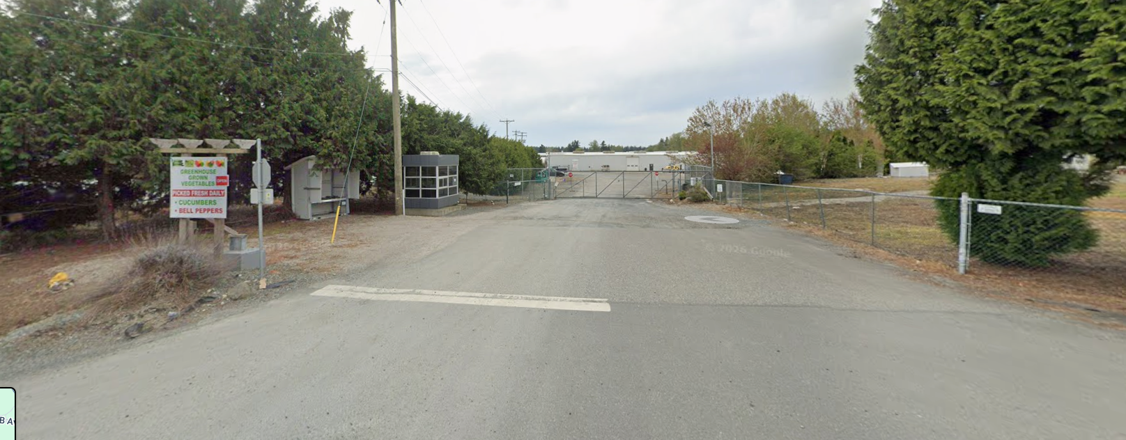 Street view of the HA Greenhouses driveway, vegetable sign and entrance gate